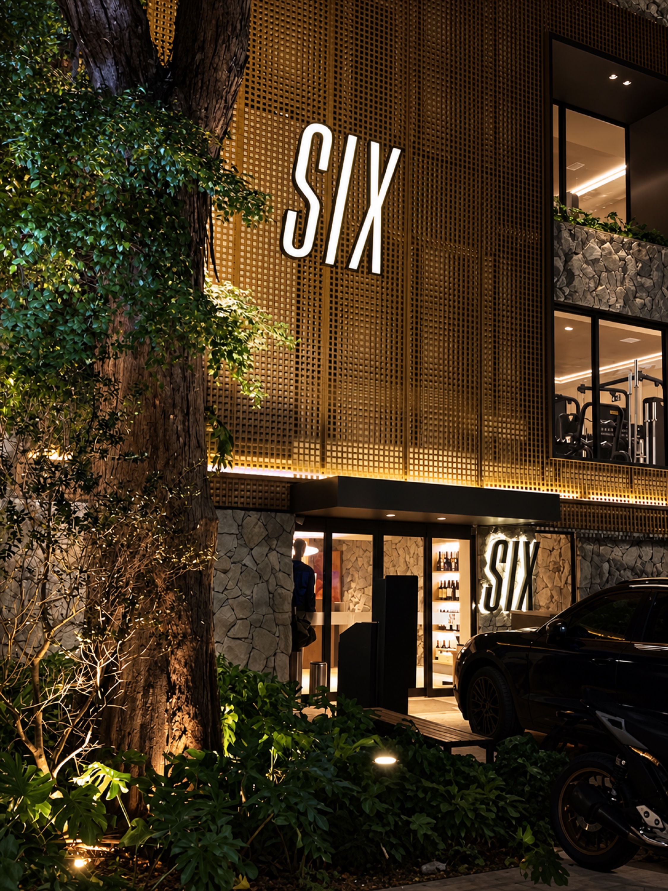 Fachada da SIX à noite, com paisagismo e iluminação quente